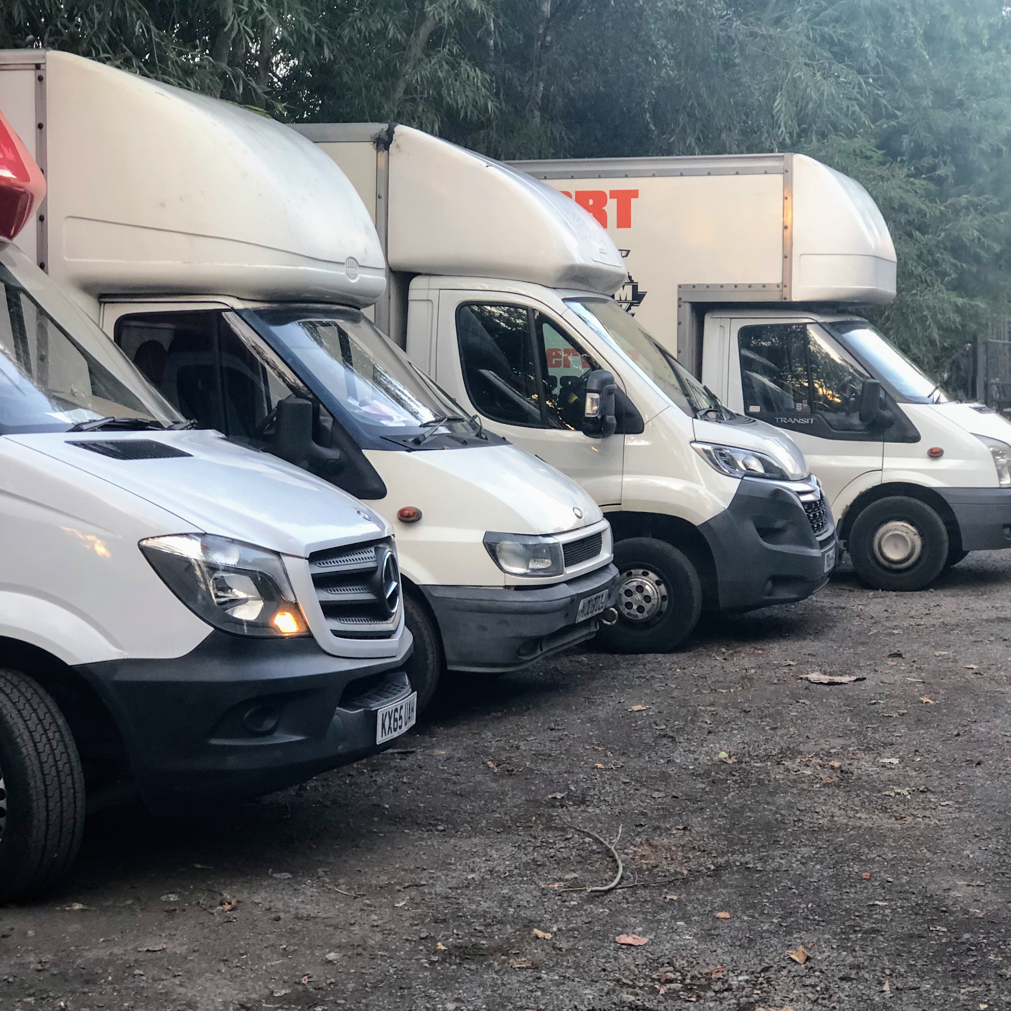 Four AJM Transport vans parked in a row, two Luton box vans and two panel vans