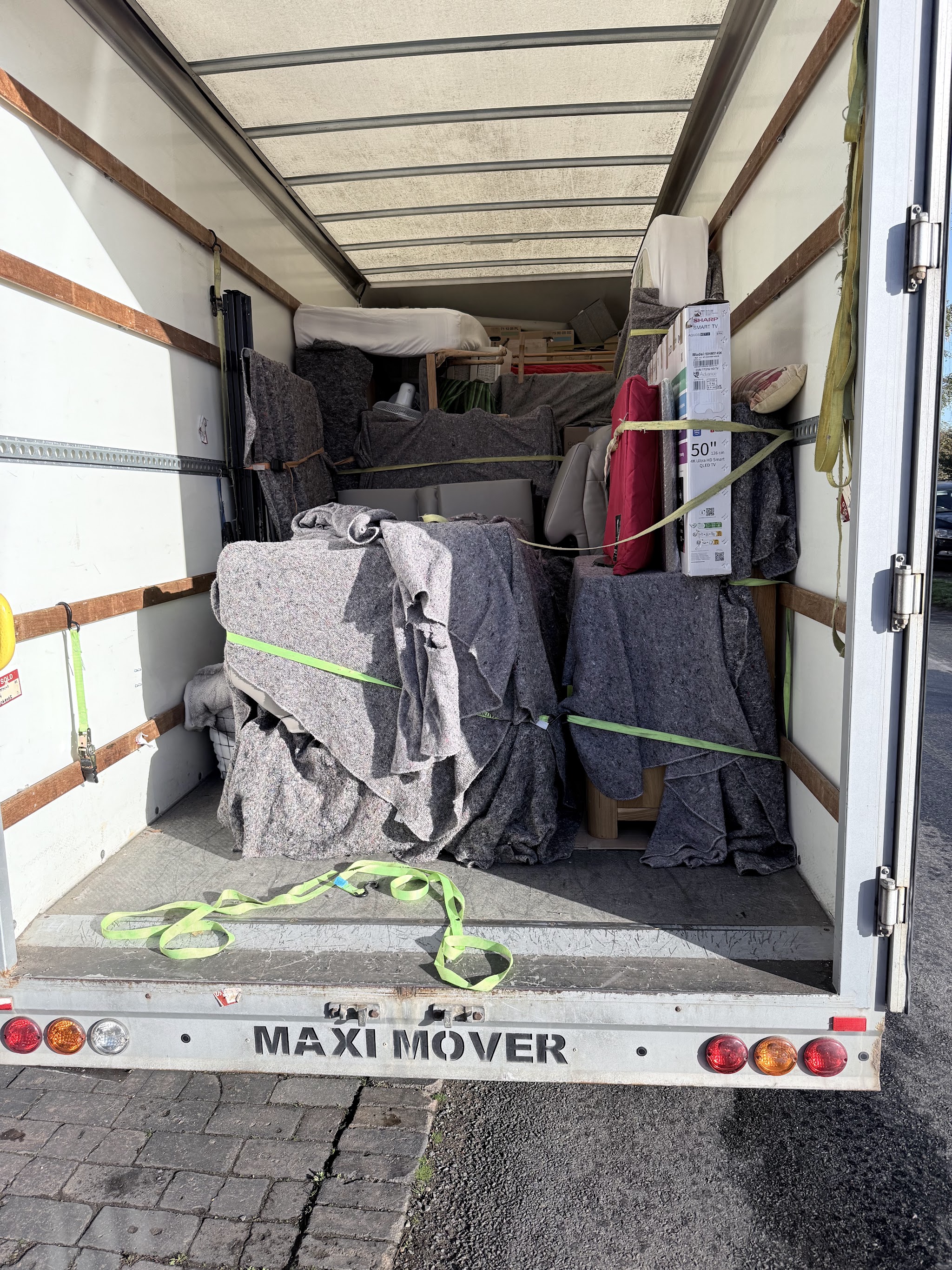 Inside an AJM Transport van: furniture wrapped in grey moving blankets and held with ratchet straps