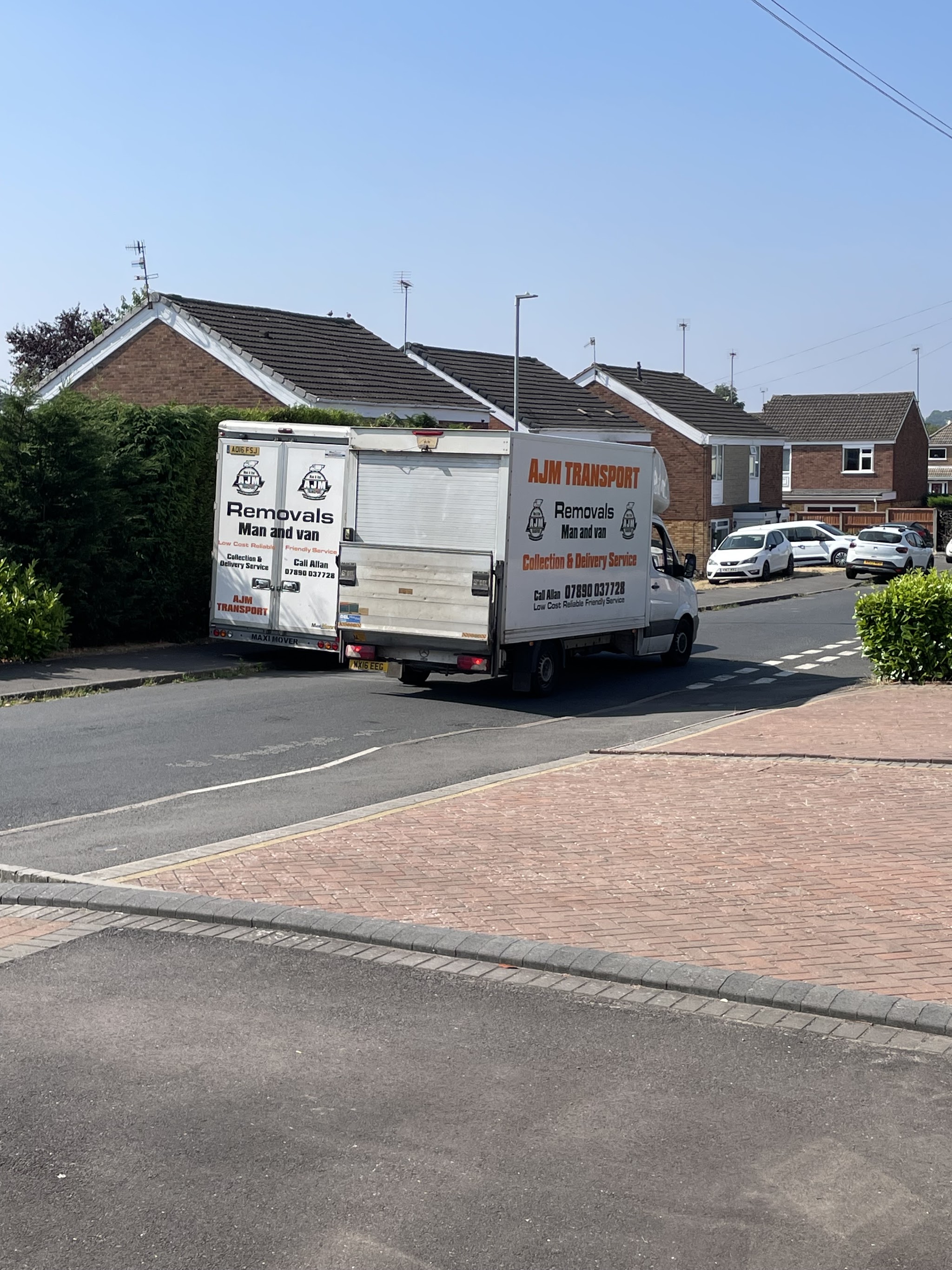 Two AJM Transport box vans parked on a residential street during a move